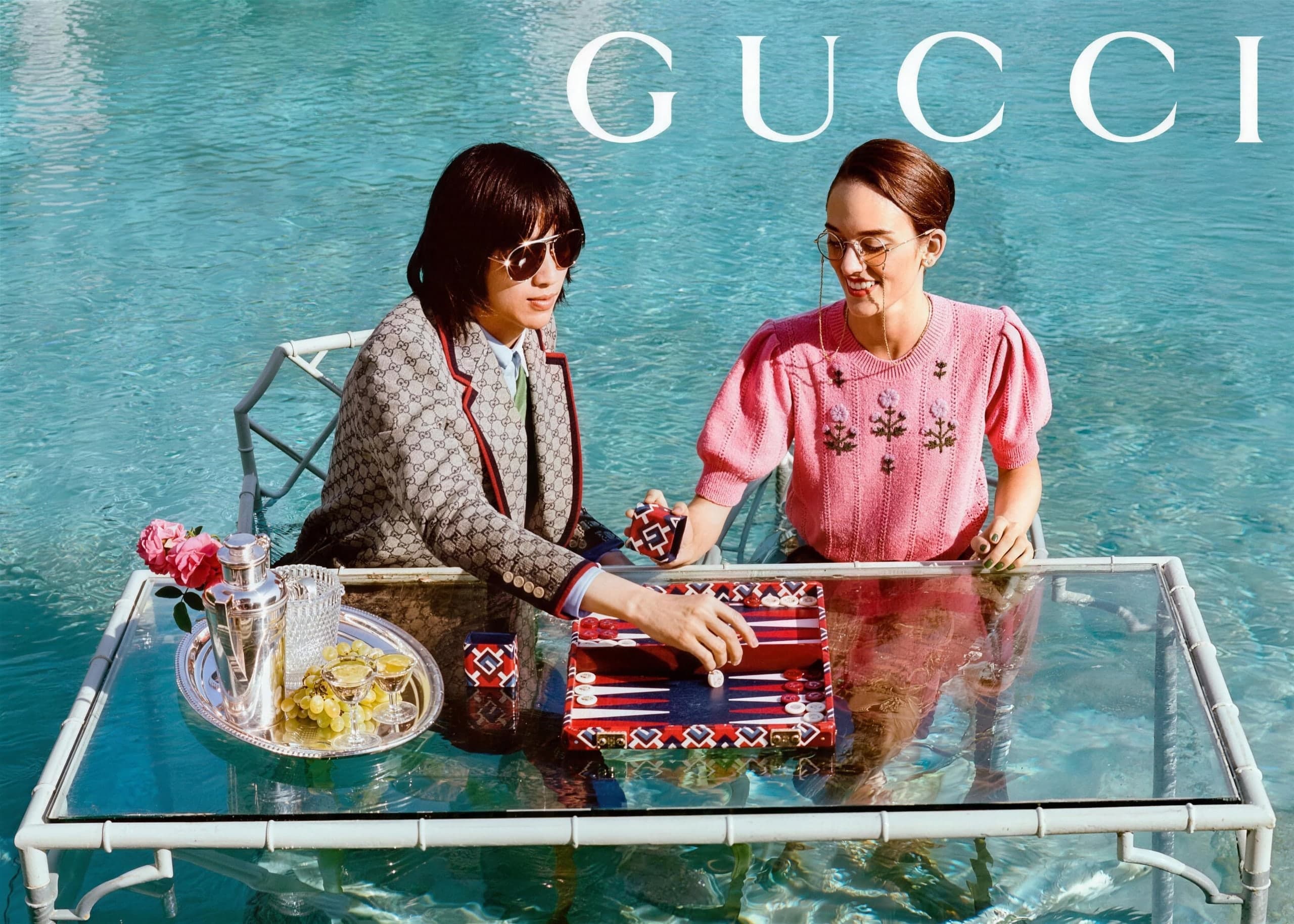 Gucci campaign: two models at a glass table set in a pool